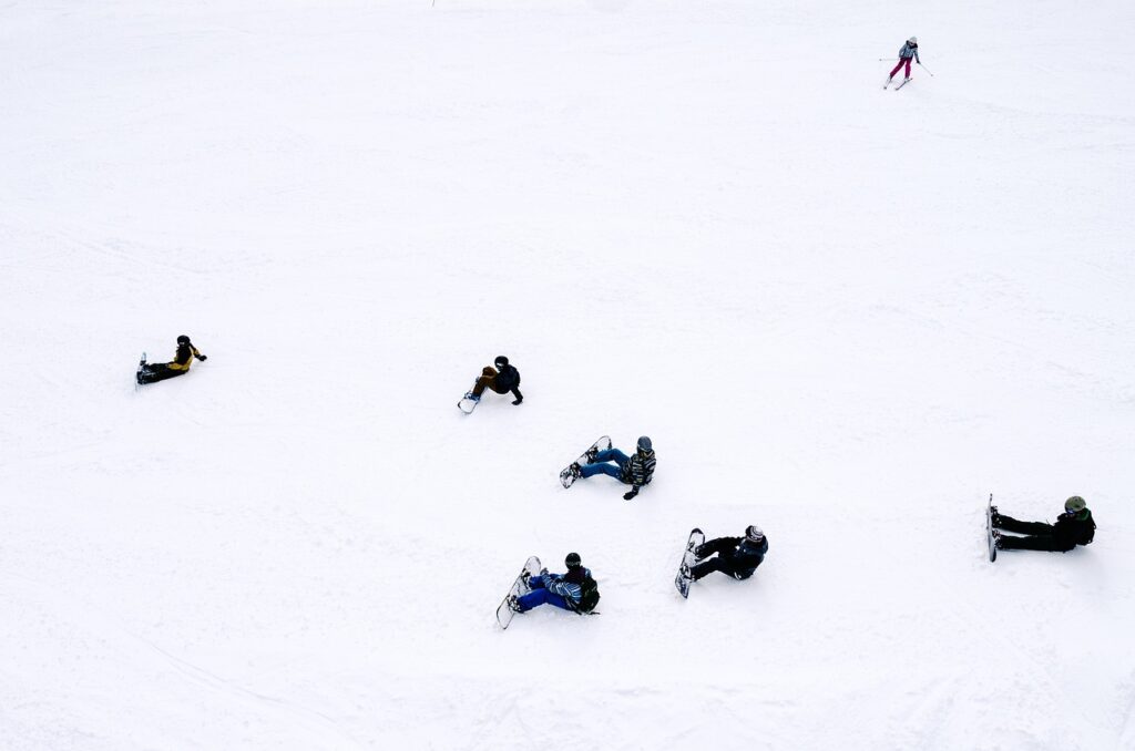 座って待つ6人のスノーボーダーの画像